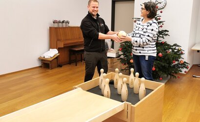 Ein Mann und eine Frau mit der mobilen Kegelbahn aus Holz